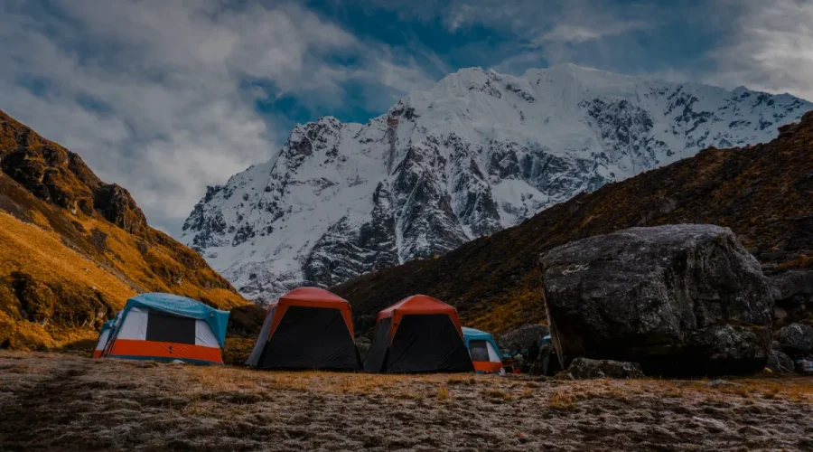 expedition tents set in a remote mountain valley beneath snow covered peaks in the Peruvian Andes