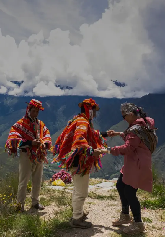 Travelers interacting with local Andean people in traditional clothing in the mountains of Cusco, Peru
