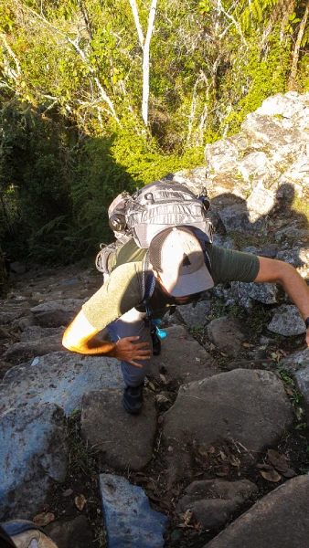 climbing rocky mountain trail Traveler climbing a steep rocky trail while carrying a hiking backpack in the Peruvian Andes