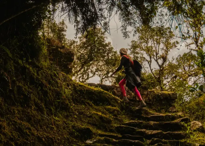 Traveler demonstrating how to prepare for the Inca Trail by hiking uphill with a backpack in the Peruvian Andes