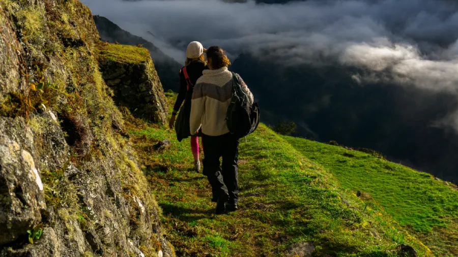 travelers hiking andean mountain trail Two travelers walking along a scenic mountain trail surrounded by clouds in the Peruvian Andes