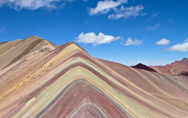 The Colors of Rainbow Mountain Colorful mineral layers across the slopes of Rainbow Mountain beneath a clear blue sky