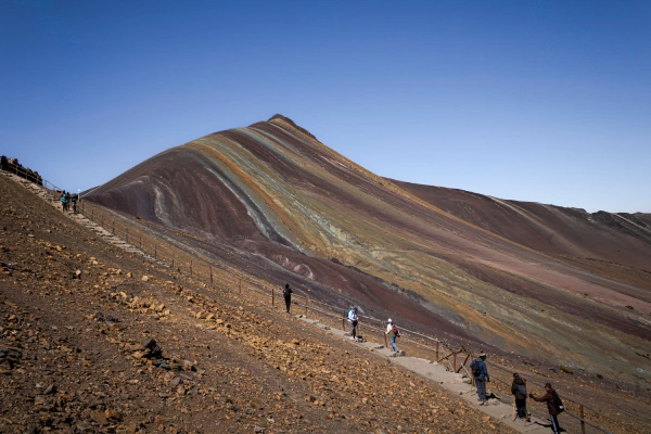 Hikers walking along the trail toward the colorful slopes of Rainbow Mountain in Peru