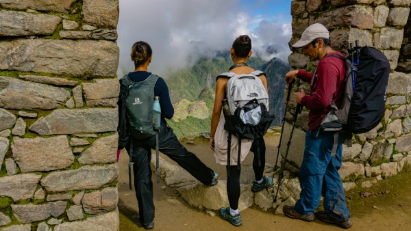 The Legendary Sun Gate Travelers arriving at a stone gateway overlooking the mountains near Machu Picchu