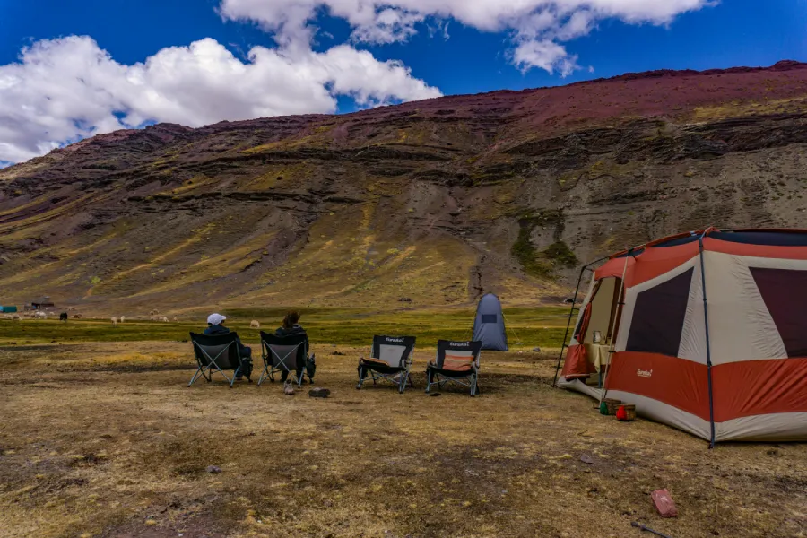 Trekking camp with tents and resting hikers in a remote mountain valley