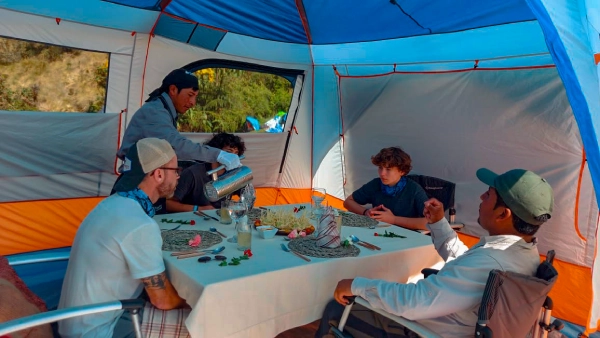 Travelers enjoying a meal inside a comfortable glamping tent