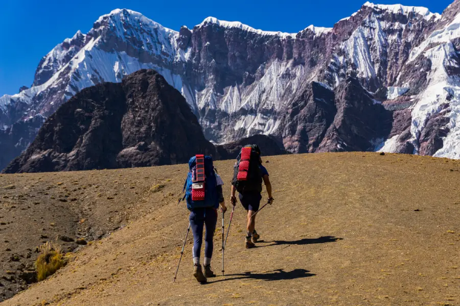 Two hikers wearing trekking clothing and carrying backpacks in the high mountains of Peru
