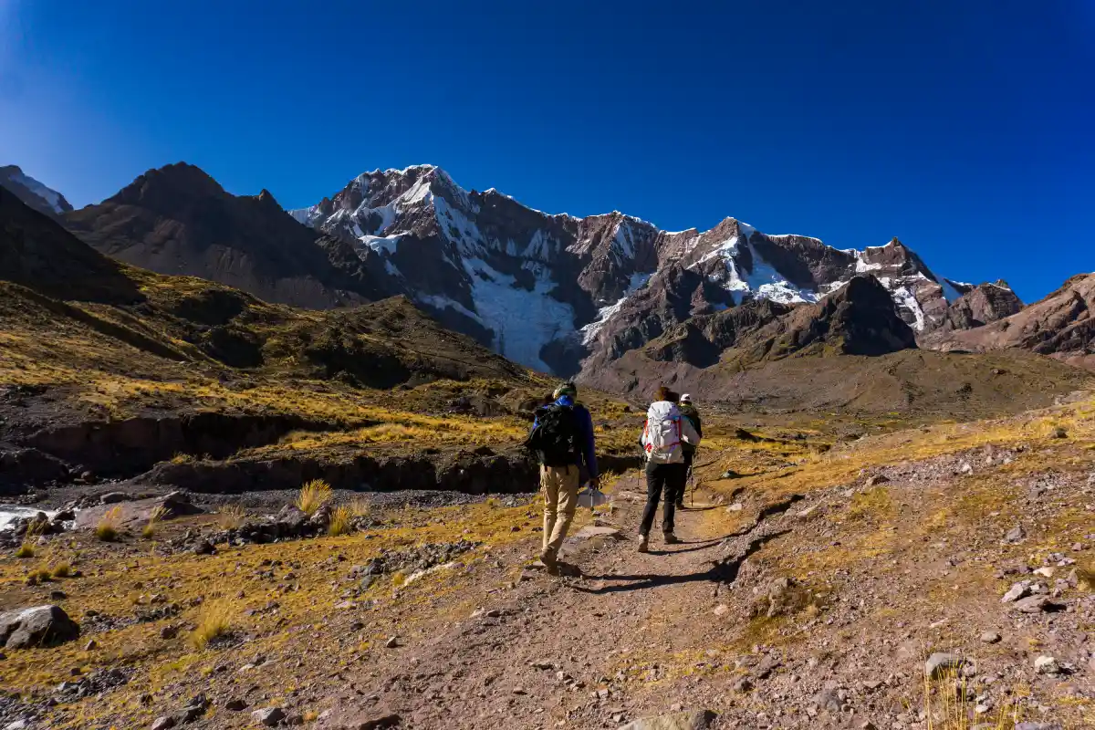 What to Pack for the Ausangate Trek: hikers carrying essential gear through the Peruvian Andes