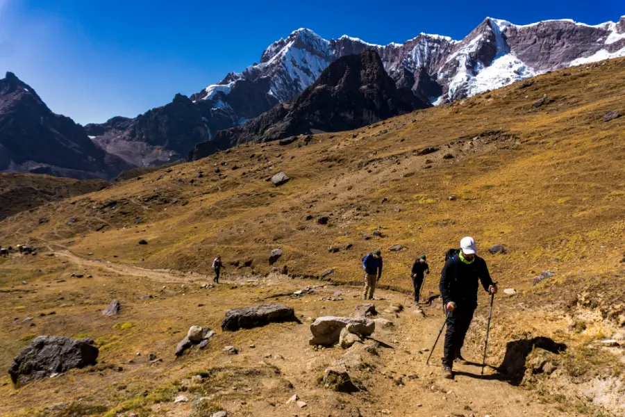 Hikers walking at different distances along a rocky trail in the Peruvian Andes