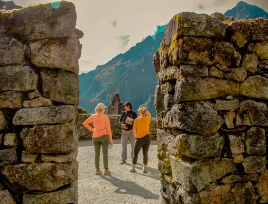 Local guide talking with two travelers at an ancient Inca archaeological site.