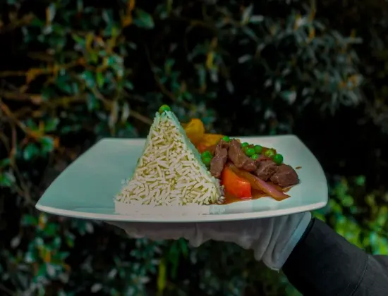Peruvian meal with rice, beef and vegetables served on a white plate.