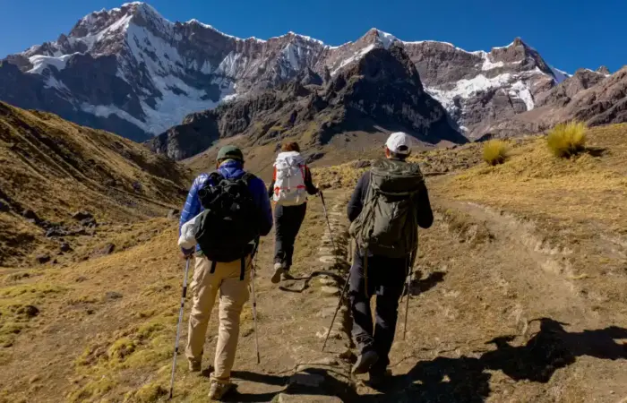 Luxury trekking packing list for Peru with hikers carrying backpacks and trekking poles in the Andes