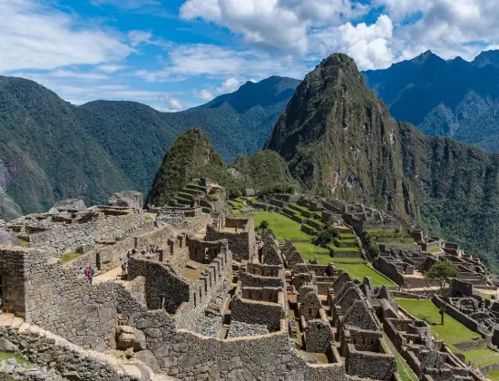 Machu Picchu's ancient stone terraces surrounded by green Andean mountains.